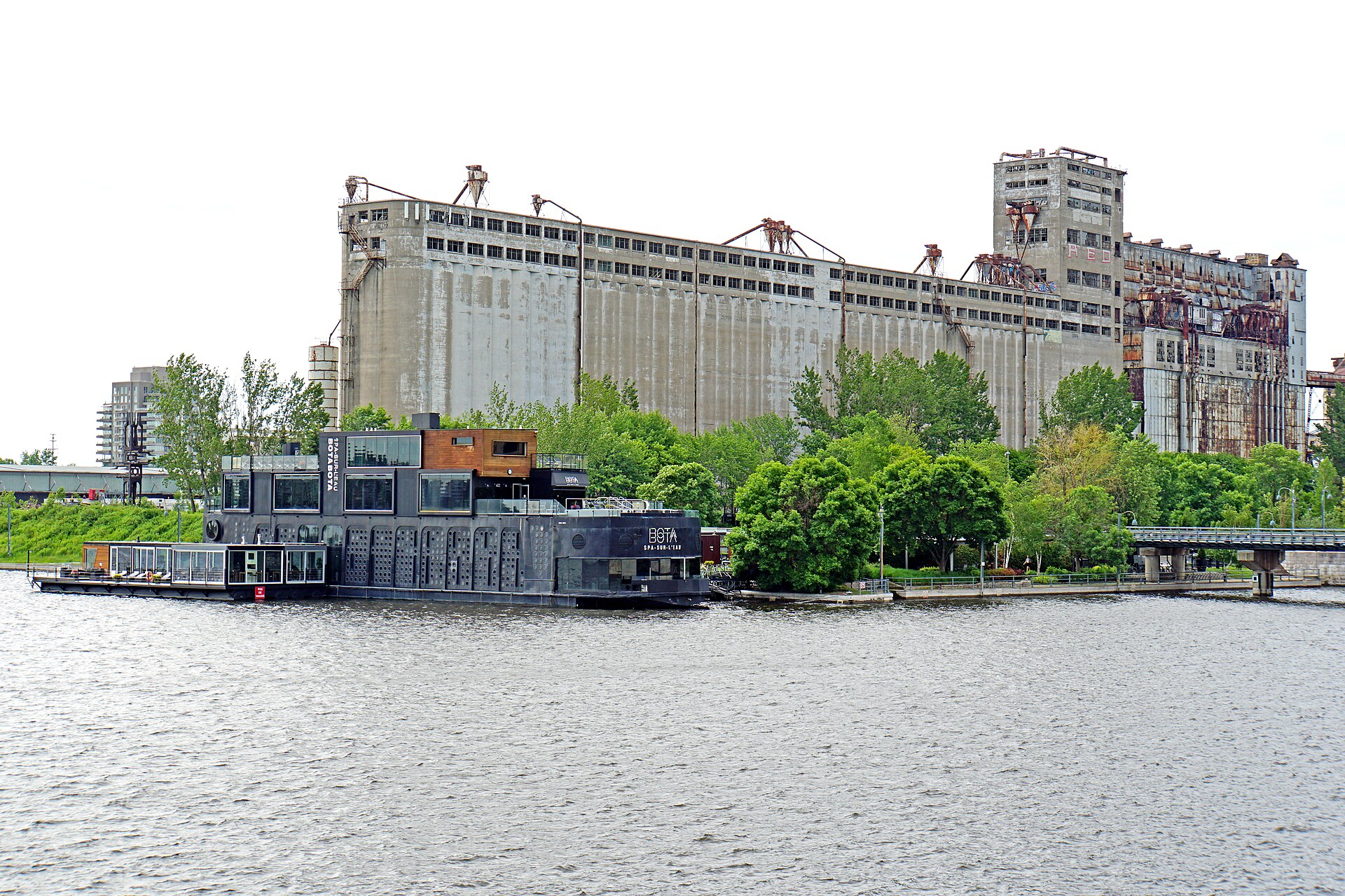 Bota Bota floating spa boat moored in Montreal's Old Port, a Nordic spa in Montreal, with grain elevators behind
