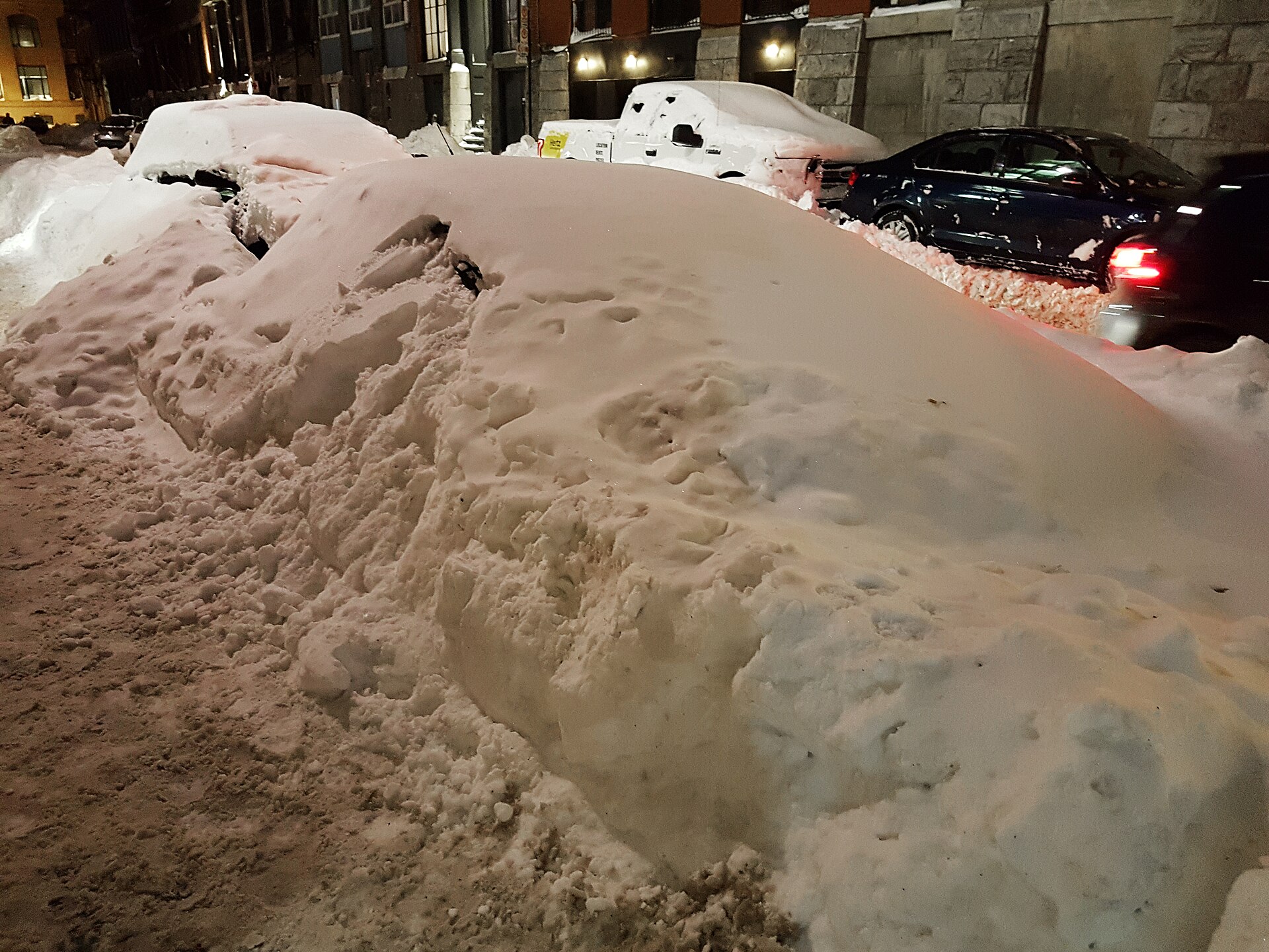 Car buried in snow on a Montreal street after a blizzard, a reminder of why winter tires in Quebec are mandatory from Dec. 1